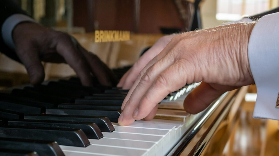 Close up of hands typing on a laptop keyboard with code on screen